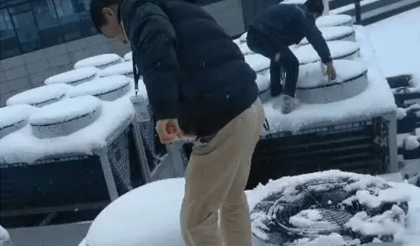 two technicians are cleaning the snow on heat pump units